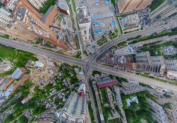 Fototapeta premium Abstract aerial view of square in the city with traffic, streets and a lot of tall colored buildings with green trees with drop effect perspective. The point of an air strike in a game or in war.