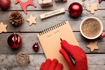 Woman writing letter to Santa at wooden table, top view