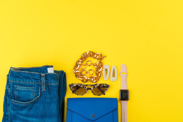 Trendy woman outfit with accessories on bright yellow background