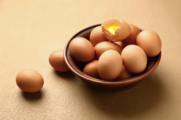 Bowl with fresh eggs on color background