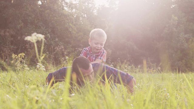 dad and son happy lifestyle family play push ups slow motion funny video . father man and son little a boy push ups in nature laugh and play