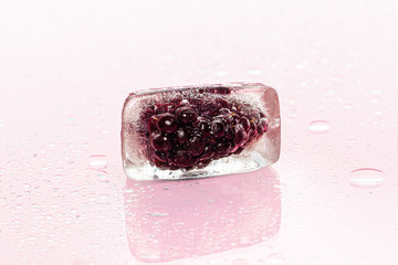 Frozen berries in ice cubes on pink