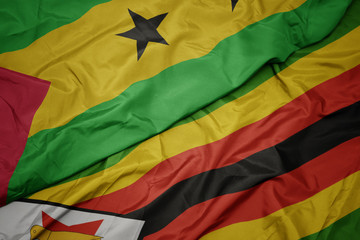 waving colorful flag of zimbabwe and national flag of sao tome and principe .