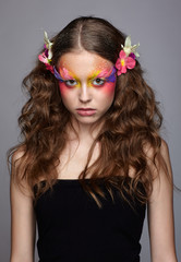 Portrait of teen girl with orchid flower in wavy hair.