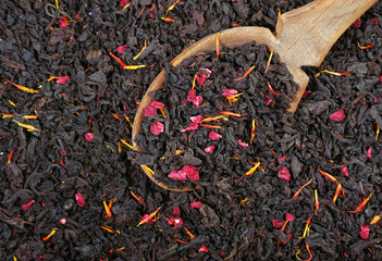 black blended tea with flower petals and dried fruits texture background. black blended tea in a...