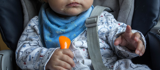the baby holds a spoon in his hands in the kitchen