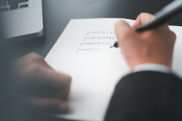 businessman write words on notebook, swot analysis concept