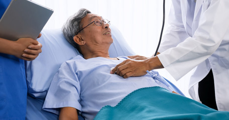 Doctor doing medical checkup for adult patient at hospital room.