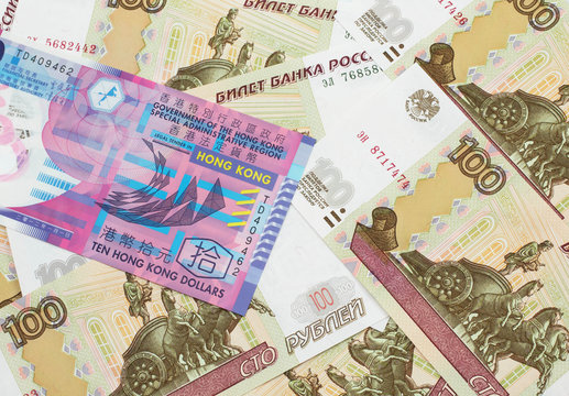 A close up image of a colorful Hong Kong ten dollar bill in macro on a bed of Russian one hundred ruble bank notes
