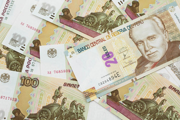 A close up image of a new, Peruvian twenty sol bank note close up on a bed of Russian one hundred ruble bank notes in macro