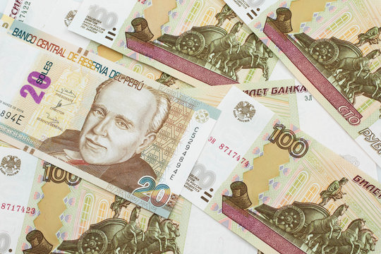 A close up image of a new, Peruvian twenty sol bank note close up on a bed of Russian one hundred ruble bank notes in macro