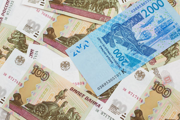 A close up image of a blue, two thousand, West African franc bank note in macro on a background of United States one dollar bills