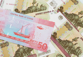 A close up image of a colorful fifty pound bank note from Sudan on a background of Russian one hundred ruble bank notes