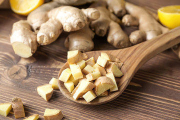 Spoon with fresh ginger on wooden table