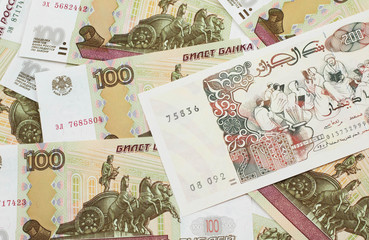 A macro image of a beige two hundred Algerian dinar bank note on a background of Russian one hundred ruble bank notes