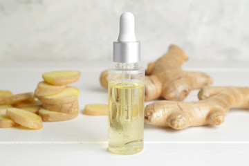 Bottle with ginger essential oil on white table