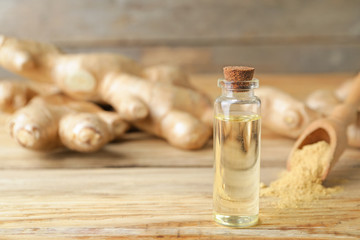 Bottle with ginger essential oil on wooden table