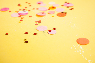 Colorful confetti, sparkles on bright yellow background. Festive background.