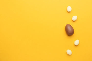 Brown chocolate Easter egg among white ones on color background. Concept of uniqueness