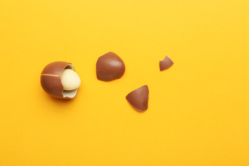 Broken chocolate Easter egg on color background