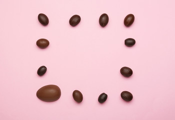 Frame made of chocolate Easter eggs on color background