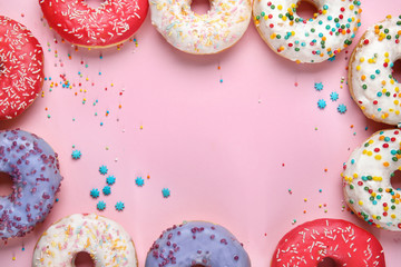 Frame made of sweet tasty donuts on color background