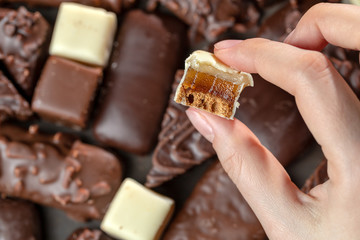 Assortment of chocolate handmade. Female hand holds tasty marmalade candy in white chocolate.