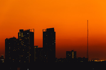 Fototapeta na wymiar Shadow city high building silhouette orange sky high rise condominium city view.