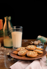 A glass of milk with Christmas cookies, nuts, gifts on the table.