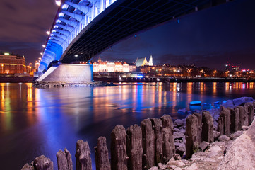 Stare miasto w Warszawie i Most Śląsko-Dąbrowski widziany z perspektywy rzeki Wisły. Sfotografowany na długim czasie naświetlania zimowa porą tuz po zmierzchu - obrazy, fototapety, plakaty