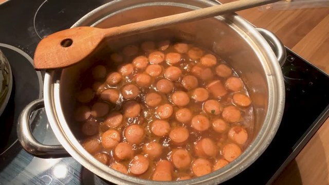 Cooking sausages in a pot with lentils