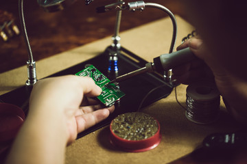 Hands of man holding solder iron  soldering the pin on electronics circuit board,  DIY hobbies and...