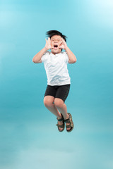Obraz premium childhood, expressions and people concept - portrait of smiling boy jumping over light background