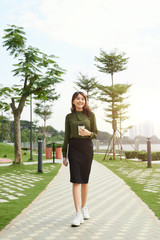 Elegant successful bsuiness woman walking outdoors with cup of take away coffee