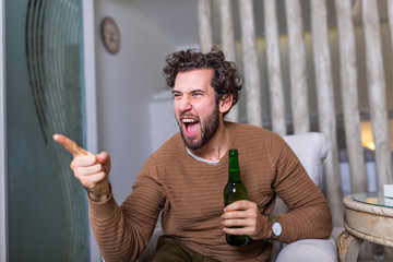 Excited sports fan sitting in an sofa and watching a match on television. leisure, sport,...