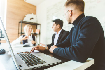 A team of young businessmen working and communicating together in an office. Corporate businessteam and manager in a meeting.