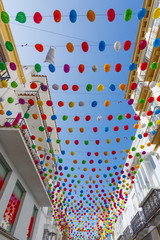 Multi-colored paper lanterns in the sky over a city street. Ronda, Andalusia, Spain.