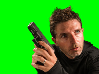 chroma key green background action portrait of serious and attractive hitman or special agent man...
