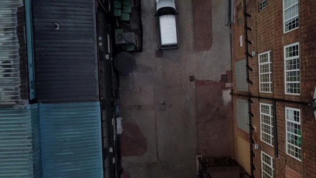 Accending drone shot from a carpark above warehouses.