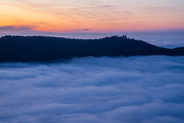 Germany, Magical aerial view above fog clouds in valley of swabian jura nature landscape at sunset...