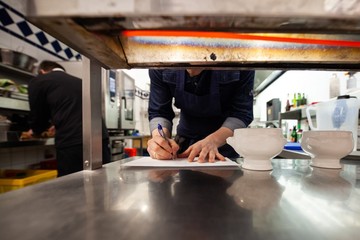chef taking notes in commercial kitchen