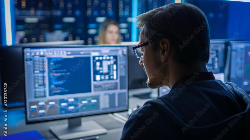 Poster Smart Male IT Programer Working on Desktop Computer in Data Center Technical System Control Room. Team of Young Professionals Programming in Coding Language