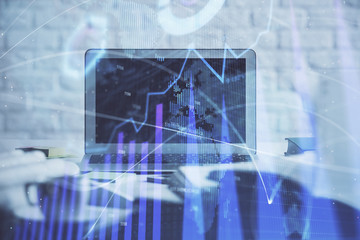 Stock market graph on background with desk and personal computer. Multi exposure. Concept of financial analysis.