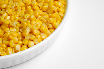 canned corn in white plate top view. white background closeup	