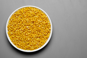 canned corn in white plate top view. grey background