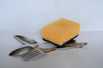 yellow sponge, spoons and fork on a white background