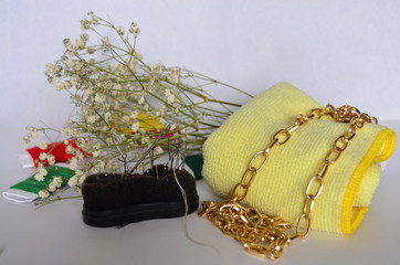 Gold chain on yellow fabric, spools of multi-colored threads, sewing needles and gypsophila