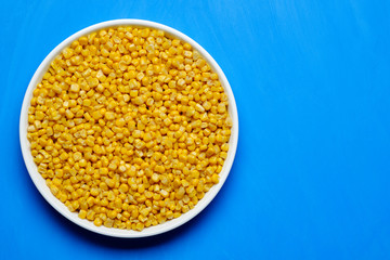 canned corn in white plate top view. blue background