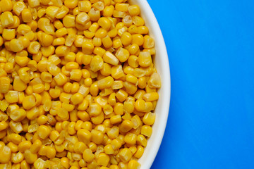 canned corn in white plate top view. blue background	