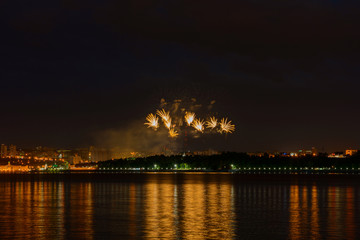 June 23, 2019: Fireworks over the night city by the river. Cheboksary. Russia.